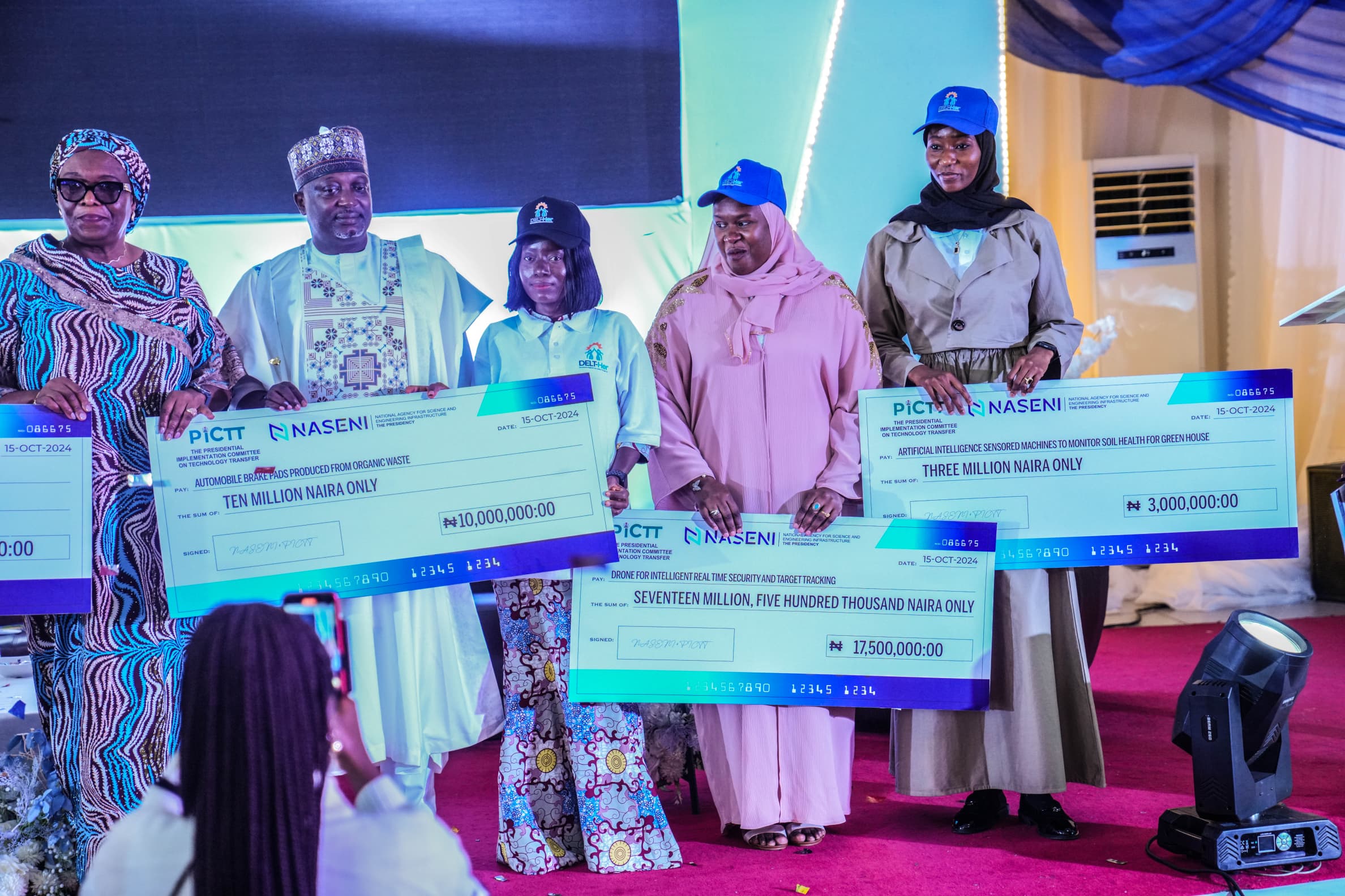 L-R: Representative of the EVC/CEO of National Agency for Science and Engineering Infrastructure, Dr. Mrs. Nonyem Onyechi; Chairman, Presidential Implementation Committee on Technology Transfer, Dr. Dahiru Mohammed; and some winners of the Developing Engineering Leaders Through Her (DELT-Her) initiative call for proposal at the presentation of cheques to the winners at the Agency’s headquarters, Abuja on Tuesday, October 15, 2024.