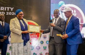 Rep of Chairman, Independent Corrupt Practices and Other Related Offences Commission (ICPC), Mr. Olusegun Adigun (middle), supported by Publisher & Editor-in-Chief, Verbatim News Magazine, Mr. Tobs Agbaebu, while presenting Verbatim Pillar of Integrity in Public Service Award 2026 to the rep of MD/CE, Nigeria Deposit Insurance Corporation (NDIC), Ms. Hawwau Gambo at the Verbatim 2026 Award ceremony in Abuja).